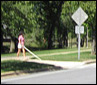 3 photos show the crosswalk; a woman holding a white cane on the ground in front of her walks to the street and puts one foot into the street, with the cane on the ground.